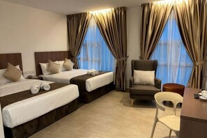 A hotel room with two beds, a chair, a desk, and large windows with curtains. - DSH Hotel (Kuala Kuantan)