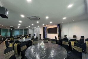 A conference room with round tables, chairs, and a projector screen. - DSH Hotel (Kuala Kuantan)