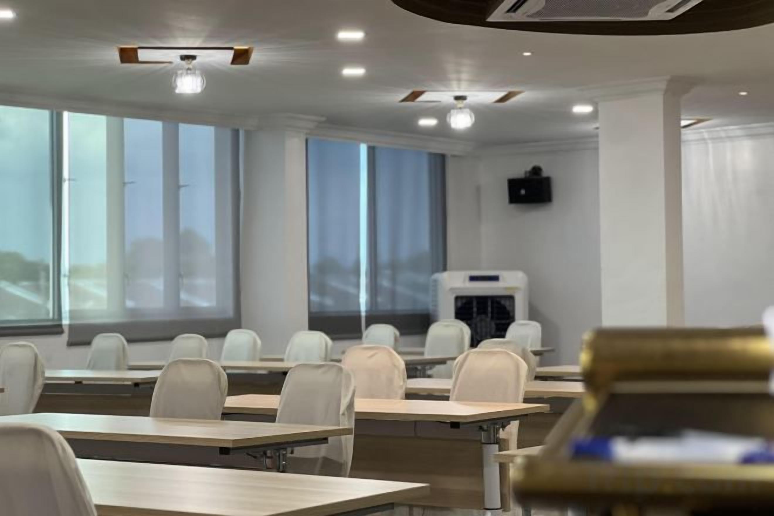 A classroom with rows of desks, chairs, and a projector screen.