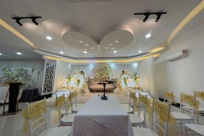 A banquet hall with a long table, chairs, and a stage with floral decorations. - DSH Hotel (Kuala Kuantan)