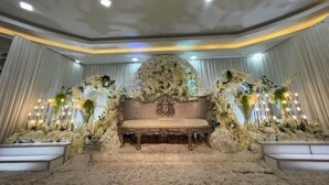 Un palco decorato con un divano elegante, circondato da composizioni floreali e tende drappeggiate.