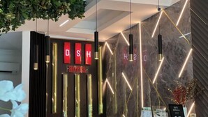 Una reception hotel dal design moderno, con un neon che riporta la scritta "DISH HOTEL" e un display digitale che mostra la tariffa di 8.7.