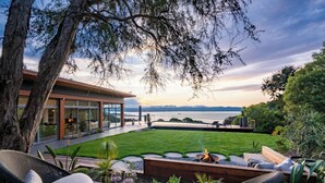 Eine moderne Terrasse im Freien mit Korbmöbeln, einer Feuerstelle und Blick auf das Meer.