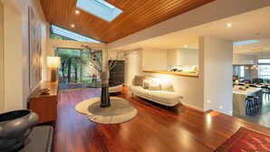 Ein modernes Wohnzimmer mit Holzboden, einer Couch, einem Couchtisch und einer Vase mit Zweigen.