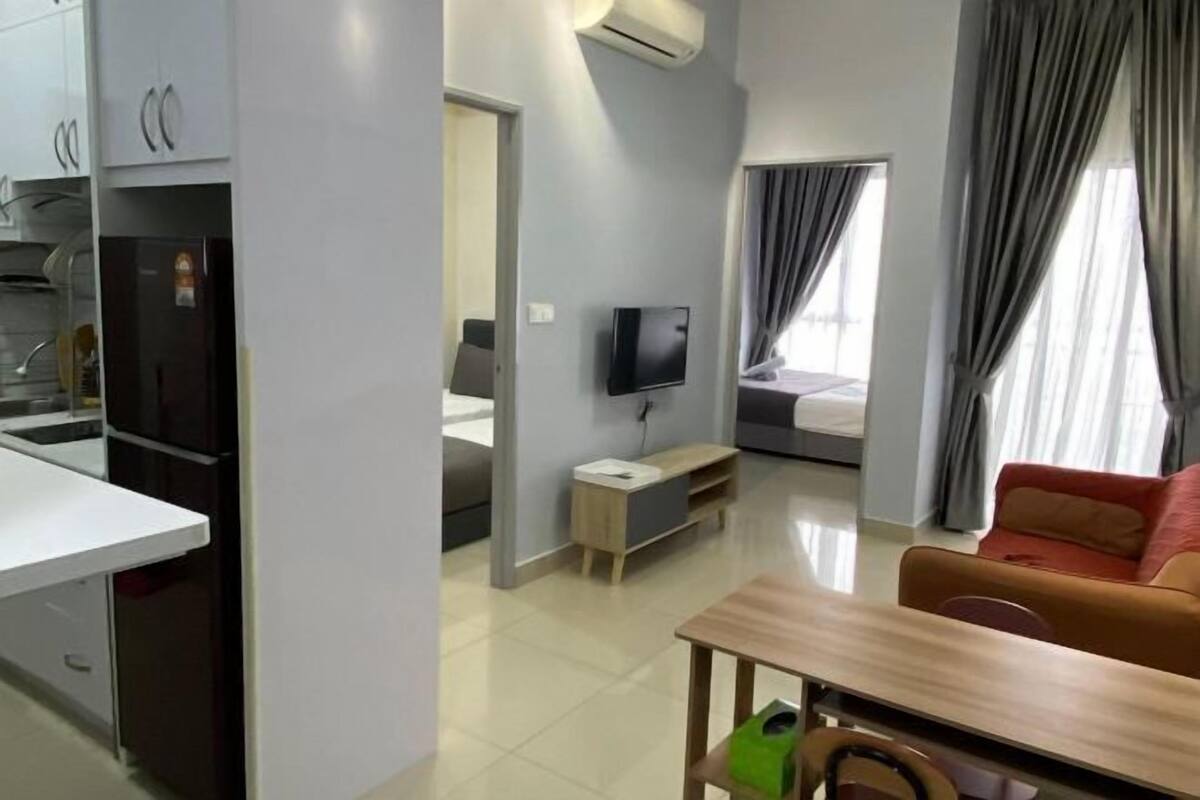 A compact hotel room with a kitchenette, a TV, a bed, and a sofa.