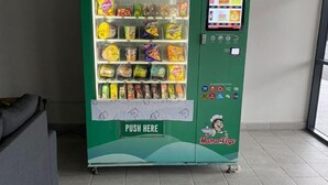 A vending machine with a green exterior and a 'PUSH HERE' button, stocked with various snacks. - Ayuman Suites, Gombak with KL City View (Gombak)