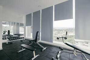 A gym with exercise equipment, large windows, and a view of the city. - Ayuman Suites, Gombak with KL City View (Gombak)