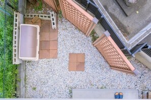 Una terraza en la azotea con zona de estar, un cubo de basura y un pequeño jardín.