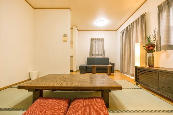 A traditional Japanese-style room with tatami flooring, a low table, a sofa, and a cabinet.