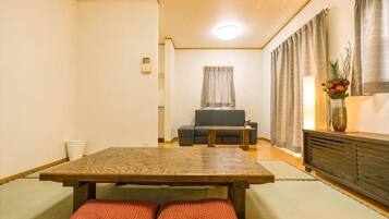 A traditional Japanese-style room with tatami flooring, a low table, a sofa, and a cabinet.