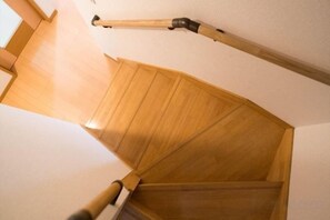 A wooden staircase with a handrail and a wooden door at the bottom. - Katsushika Takasago House (Tokyo)