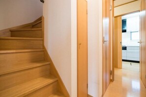 A wooden staircase leading to a kitchen area with cabinets and a countertop. - Katsushika Takasago House (Tokyo)