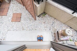 A rooftop terrace with a person standing on a ledge, a small table with a chair, and a water feature. - Katsushika Takasago House (Tokyo)