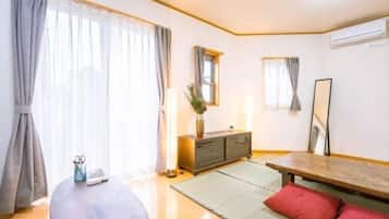 A room with a wooden bench, a small table with a vase and scissors, a cabinet, and a tatami mat.