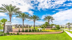 A residential area with a sign reading 'SOLARA,' surrounded by palm trees and well-maintained lawns.