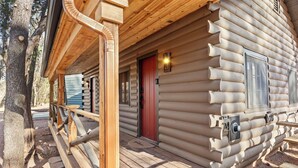 Una baita di legno con un portico in legno, una porta rossa e finestre numerate.
