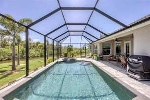Ein überdachter Swimmingpool mit Terrassenbereich, Whirlpool und Gartenmöbeln.