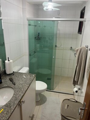 Une salle de bain avec une douche à parois de verre, des toilettes, un lavabo avec un porte-serviettes et un miroir.