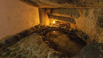 A stone interior with a circular stone pattern on the floor and a light source in the center.