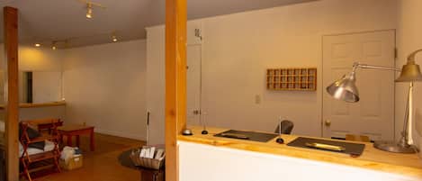 A room with a wooden table, chairs, a small desk, and a door.