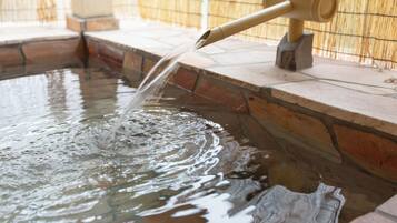 A water feature with a bamboo spout pouring water into a stone basin.