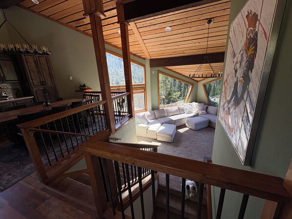 Un loft amplio con techos altos, ventanas grandes, una escalera de madera y una zona de estar acogedora.
