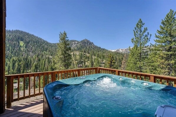 A hot tub on a wooden deck with a mountain view.
