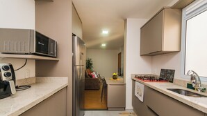 Une cuisine compacte équipée d’un four à micro-ondes, d’un réfrigérateur et d’une cuisinière à gaz.