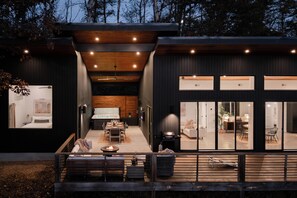 A modern house with a dining area, kitchen, and living spaces. - Luxe Asheville Retreats • Heated Pool + 2 Hot Tubs • Sleeps 16 • Views (Weaverville)