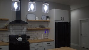 Une cuisine moderne avec un fourneau noir, des armoires blanches et des luminaires suspendus.