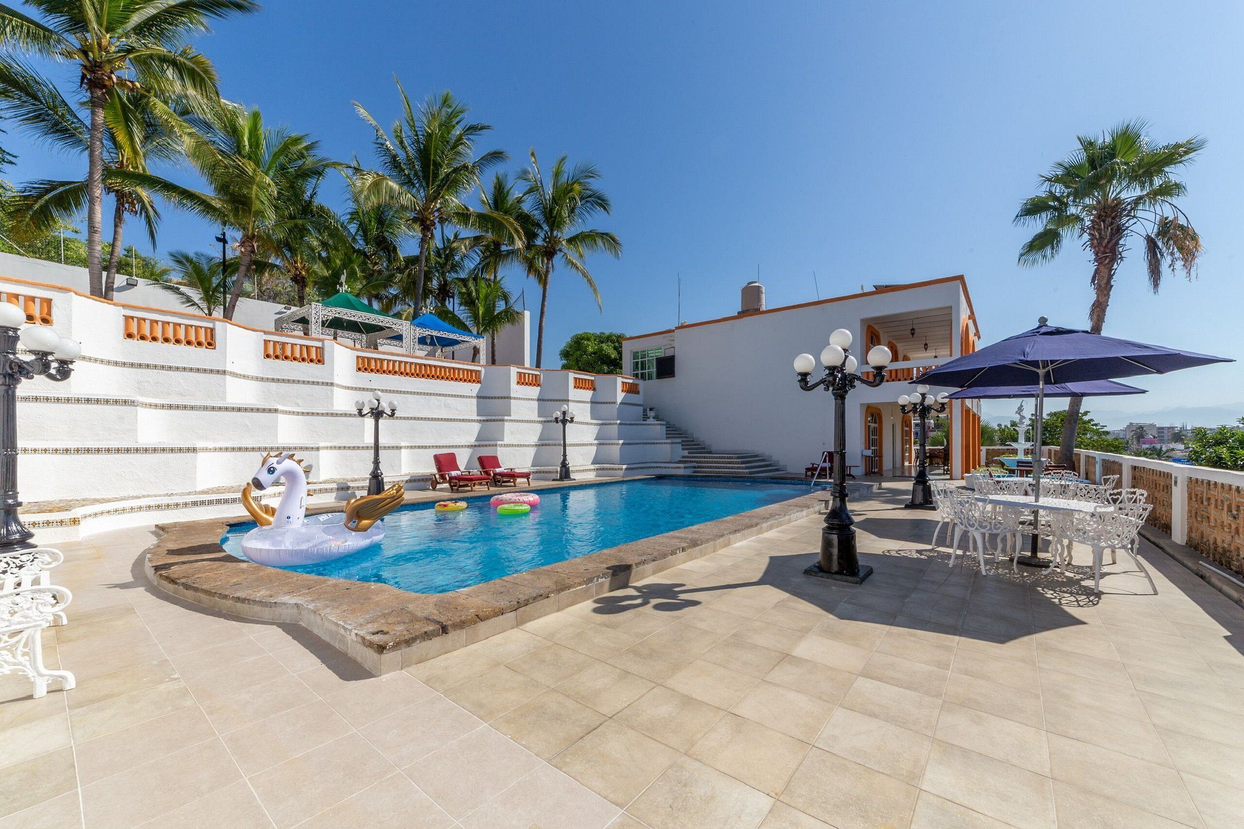 A rooftop pool area with a swimming pool, lounge chairs, and umbrellas.