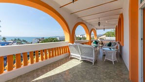 A balcony with white wicker furniture and orange railings, overlooking a coastal view. - Quinta Nayarit (Bucerías)