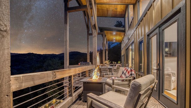 A wooden deck with a fire feature, outdoor seating, and a view of the mountains. - Wellness Retreat! Peloton, Hot Tub, Sauna, Outdoor Gym, Views, and 2 King Suites (Cherry Log)