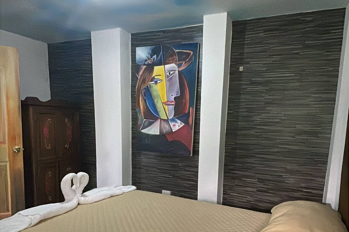 Une chambre d’hôtel avec un lit, un tableau au mur et une armoire en bois.