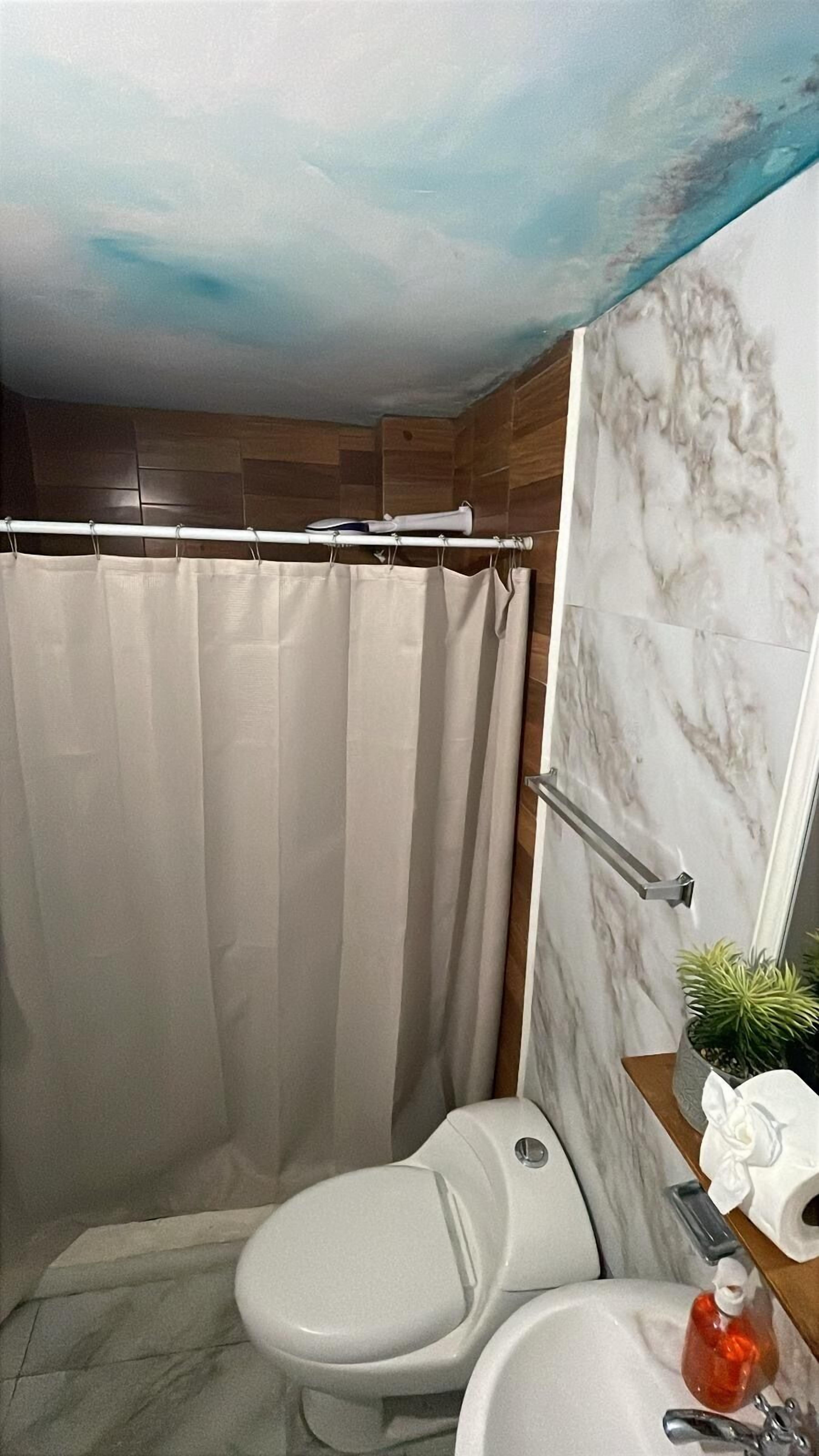 Un bagno con tenda da doccia, un water, un lavandino e una parete in marmo.
