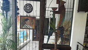 Une pièce dotée d’un plancher en bois, d’une plante en pot et d’une grille métallique ornée d’un motif décoratif.