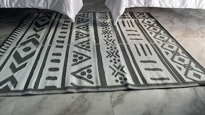 Une chambre d’hôtel avec deux lits, une fresque représentant des oiseaux au plafond, une petite table avec une lampe et une vue sur la verdure à l’extérieur.