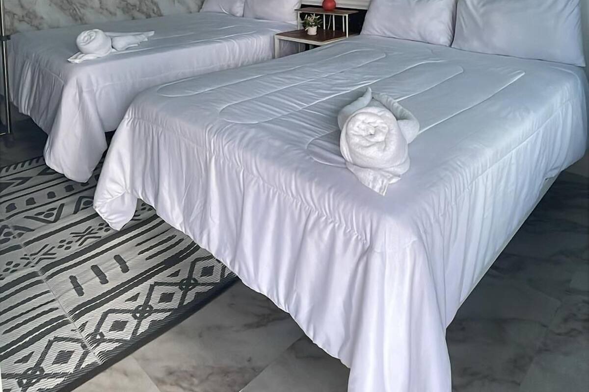 Une chambre d’hôtel avec deux lits, un mur en marbre, une fresque représentant des oiseaux au plafond et un grand miroir.