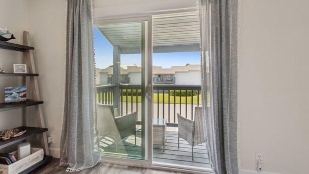 Een kamer met een schuifdeur die uitkomt op een balkon met tuinmeubilair.