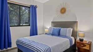 Ein Schlafzimmer mit Bett, Vorhängen, einer Wanddekoration mit Sonnenelementen und Nachttischlampen.