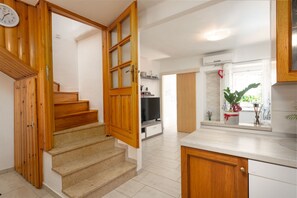A kitchen with wooden cabinets, a countertop, and a window with a plant. - House Nadia (Kvarner - Mošćenička Draga) (Mošćenička Draga)