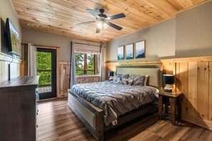 Un dormitorio con cama, ventilador de techo, mesita de noche, ventana y puerta.