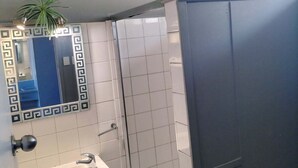 A bathroom with a white sink, a mirror with a decorative frame, a potted plant, and a shower area. - Maryborough Motel and Conference Center (Maryborough)