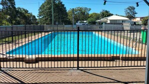 A rectangular swimming pool with a black metal fence, surrounded by a brick patio. - Maryborough Motel and Conference Center (Maryborough)