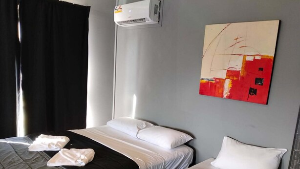 A hotel room with two beds, a painting on the wall, and an air conditioning unit. - Maryborough Motel and Conference Center (Maryborough)