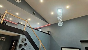 Un interior moderno con escalera, ventilador de techo, iluminación empotrada y un elemento decorativo luminoso.