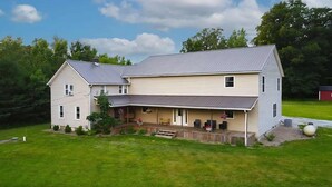 A two-story house with a covered porch and a large lawn.