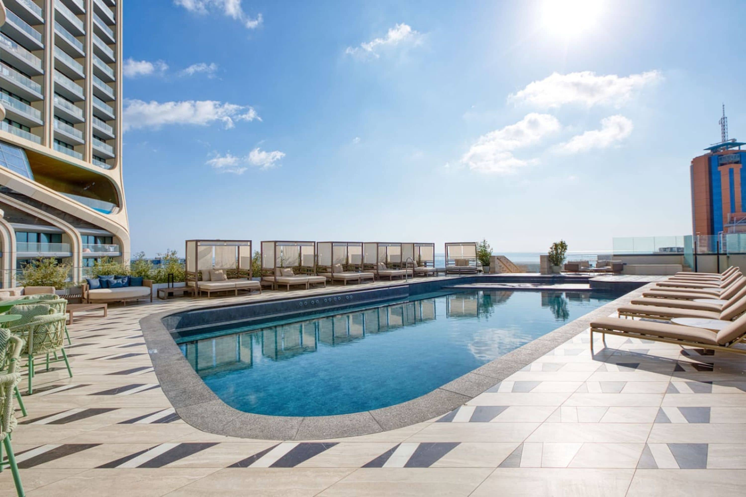 A rooftop pool area with lounge chairs and a view of the ocean.
