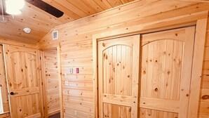 Habitación de cabaña de madera con una cama, ventilador de techo y paredes de madera.