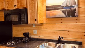 Una cocina de madera con microondas negro, cafetera y lavaplatos.